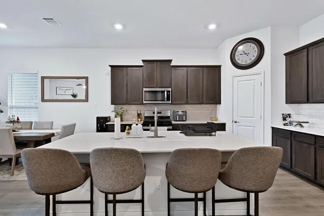 a kitchen with granite countertop a table chairs stove top oven and cabinets