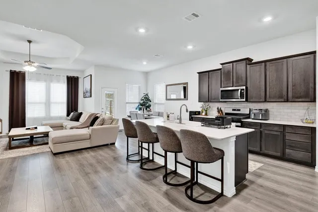 a living room with stainless steel appliances granite countertop furniture a couch and a view of kitchen