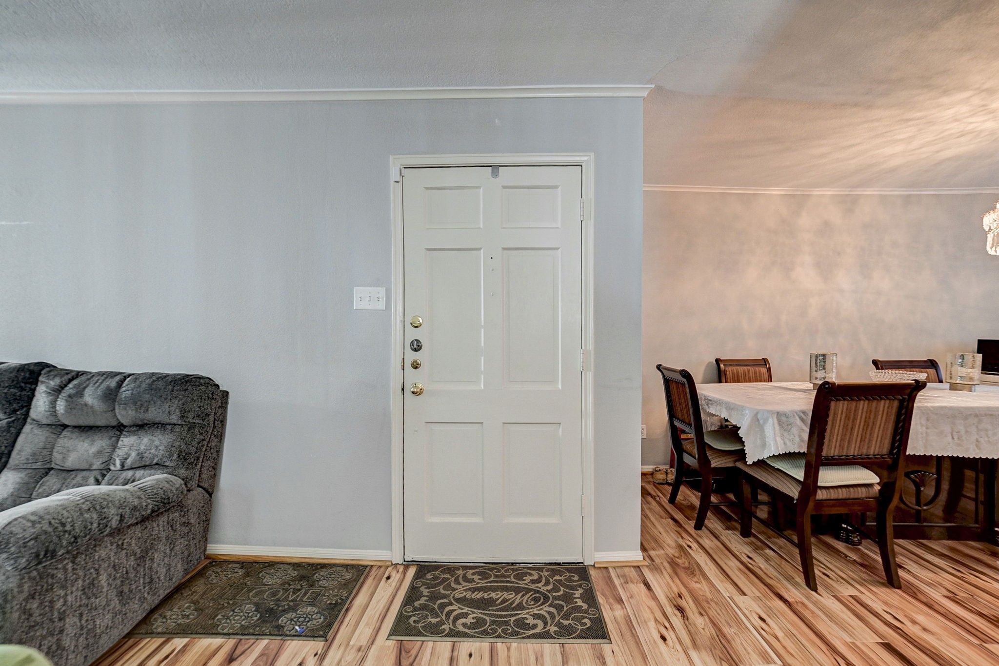 7900 Westheimer Road, Unit 202 Houston, TX 77063 - Photo 7 of 25 Inviting living space featuring a cozy gray sofa and an adjacent dining area with a stylish table setting, enhanced by warm wood flooring and soft lighting.