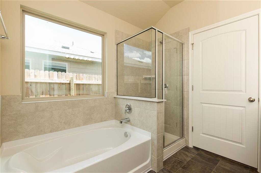 12912 Tinker Street Manor, TX 78653 - Photo 8 of 12 a bathroom with a bathtub and a shower