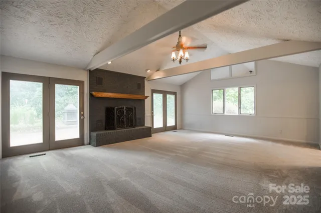 a view of an empty room with a fireplace and a window