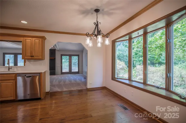 a view of an empty room with window and wooden floor