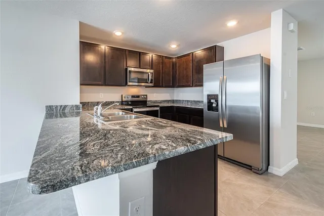 a kitchen with stainless steel appliances granite countertop a refrigerator and a sink
