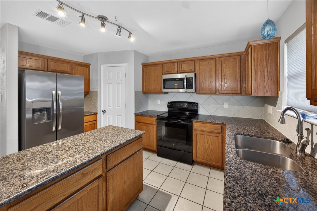 7015 Rickey Drive Temple, TX 76502 - Photo 10 of 29 a kitchen with stainless steel appliances granite countertop a sink stove and refrigerator