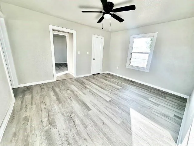 a view of empty room with wooden floor and fan