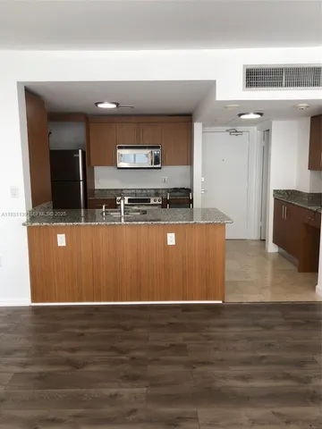 a view of a kitchen with stainless steel appliances wooden floor and chair