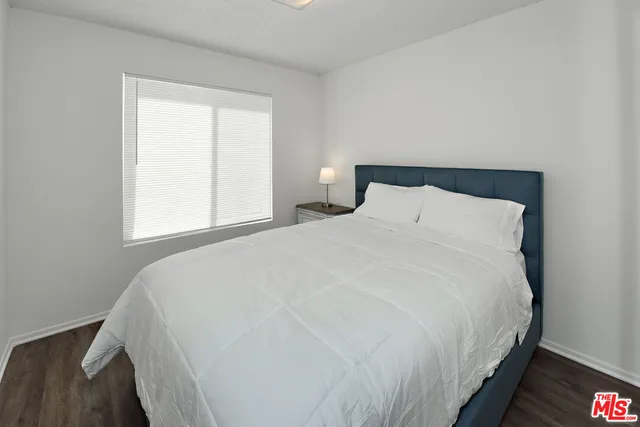 a large white bed in a bedroom next to a window