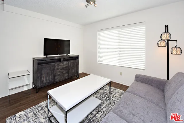 a living room with a bed furniture flat screen tv and a window