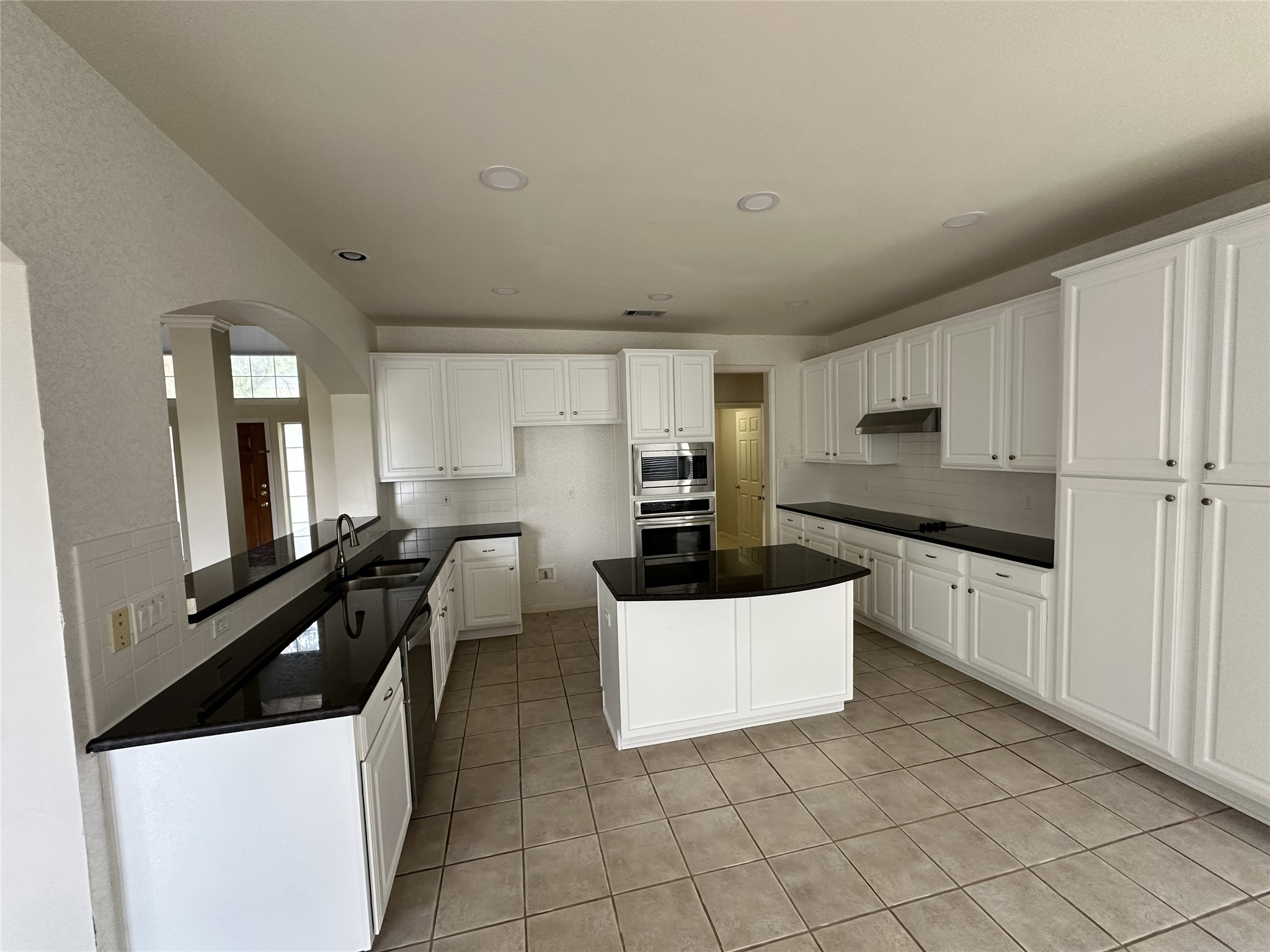 9405 Ashton Ridge Austin, TX 78750 - Photo 9 of 22 White cabinetry, dark counters, and tiled flooring define this culinary space, ready for your personal touch.