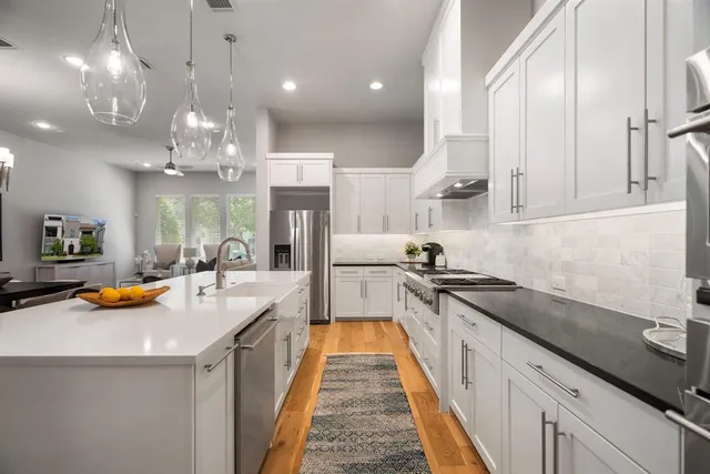 a kitchen with stainless steel appliances granite countertop a sink a stove and a wooden floors