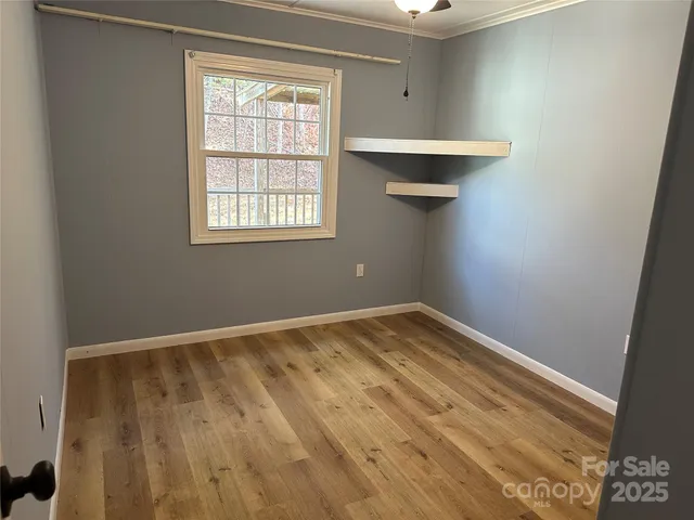 a view of empty room with wooden floor and fan