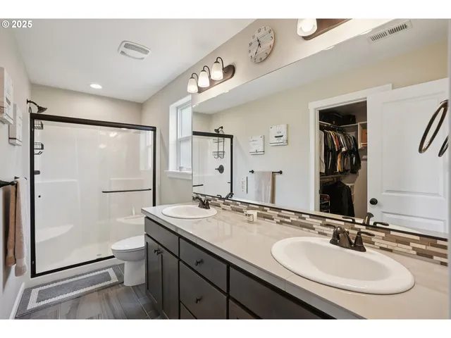 a bathroom with a sink double vanity granite tub shower and a mirror