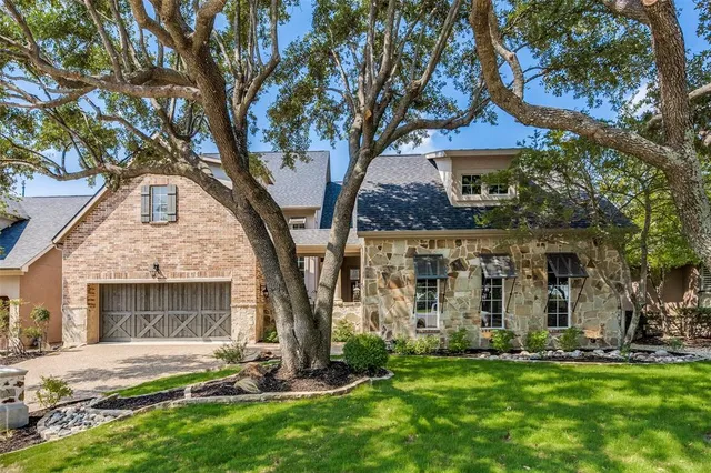 a front view of a house with a garden and tree