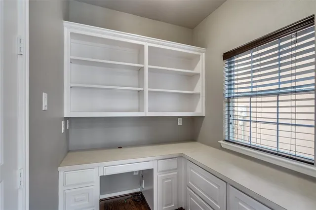 an empty room with wooden floor cabinet and windows