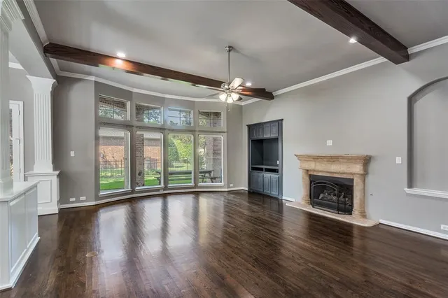 a view of an empty room with wooden floor fireplace and a window