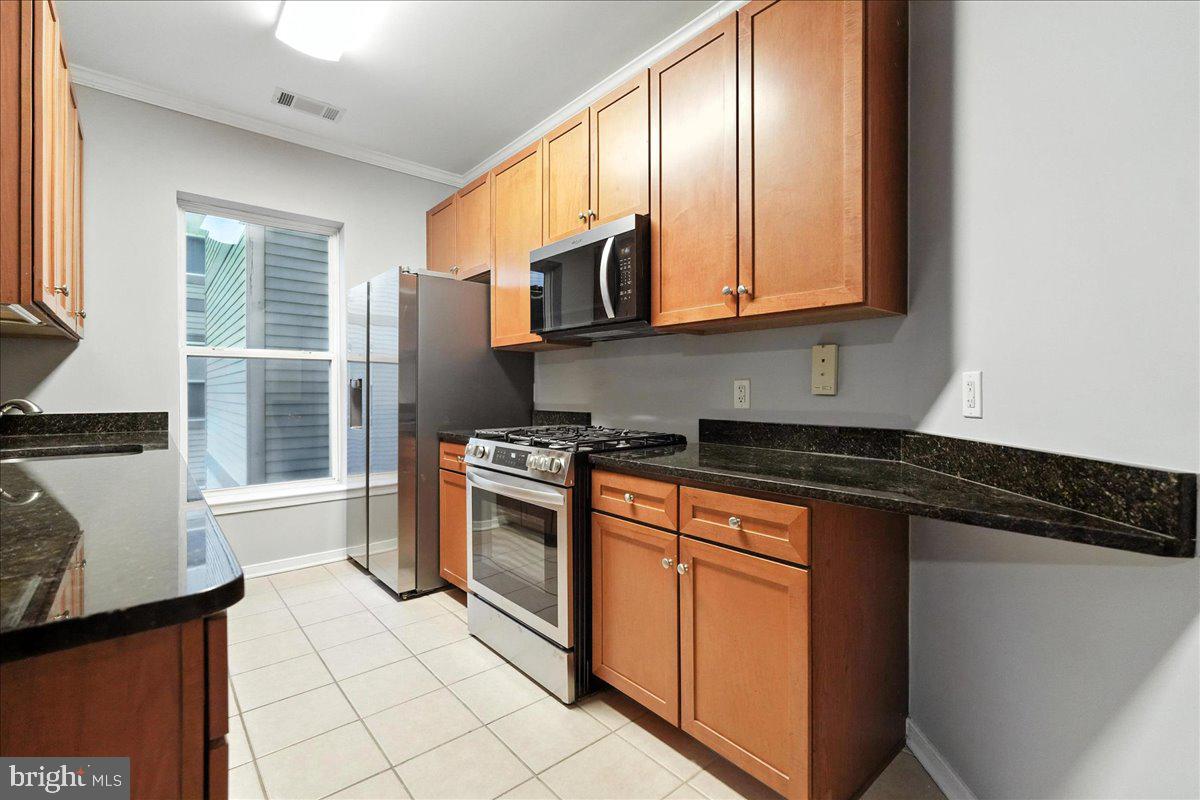 8045 Newell Street, Unit 301 Silver Spring, MD 20910 - Photo 3 of 19 a kitchen with stainless steel appliances granite countertop a stove a sink and a microwave