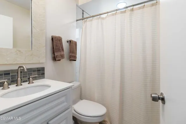 a bathroom with a sink a toilet and shower curtain