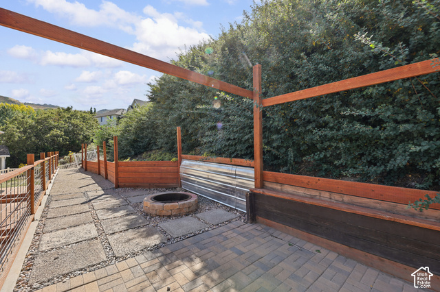 14038 New Saddle Road Draper, UT 84020 - Photo 35 of 46 Paver patio with a stone fire pit, wood-finish retaining wall, and integrated wood-finish planters
