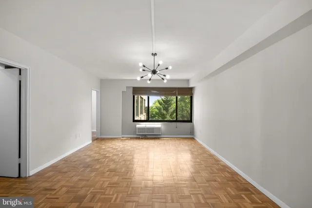 a view of an empty room with window and chandelier