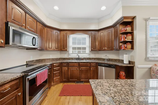 a kitchen with stainless steel appliances granite countertop a stove a sink dishwasher and a microwave oven with cabinets