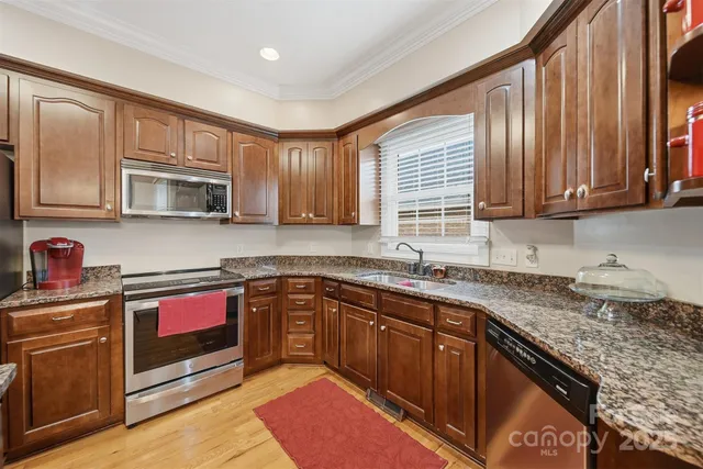 a kitchen with stainless steel appliances granite countertop wooden cabinets a sink and dishwasher