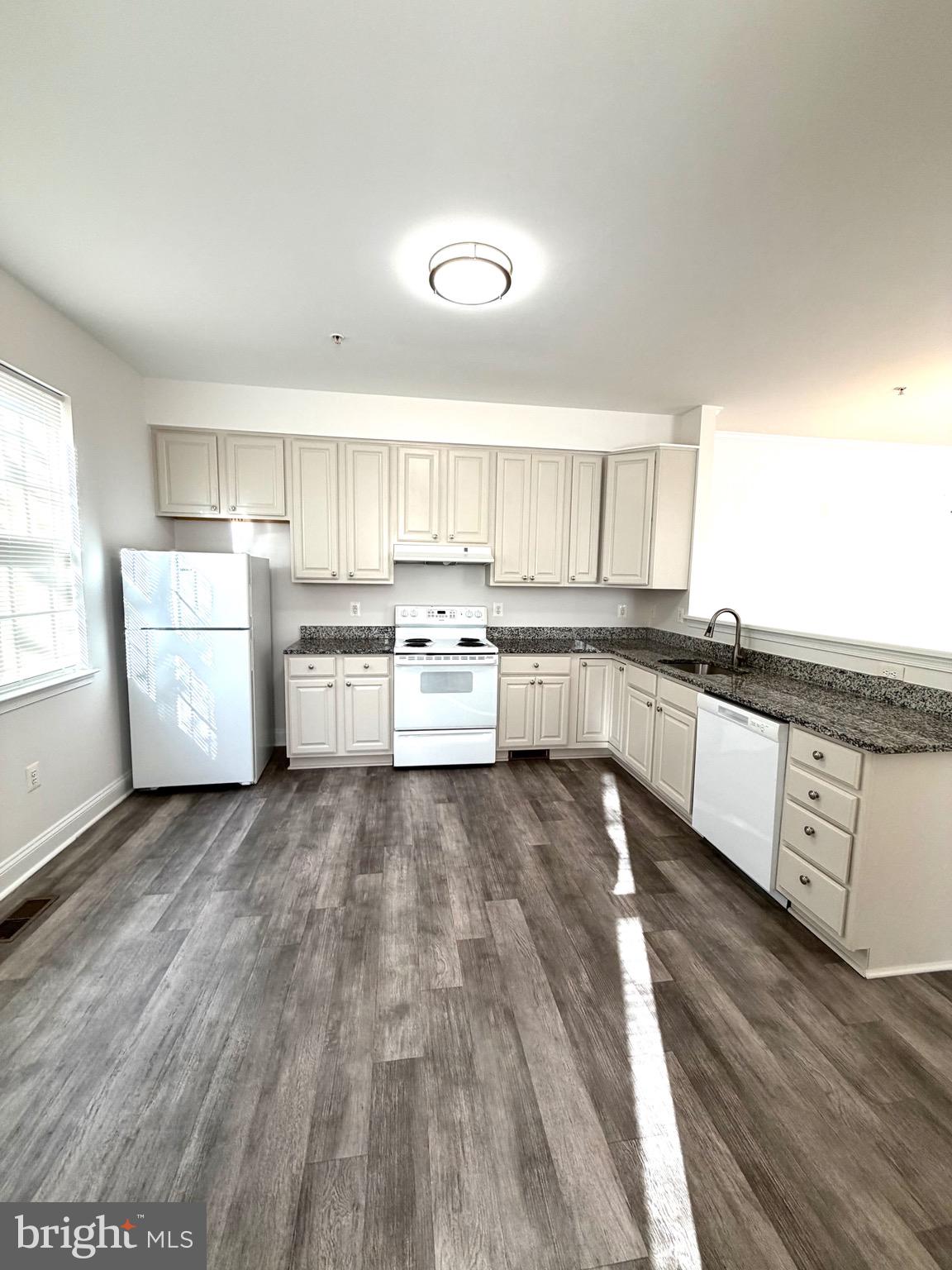 107 A Burck Street, Unit A Frederick, MD 21701 - Photo 12 of 22 a large kitchen with wooden floors and white stainless steel appliances