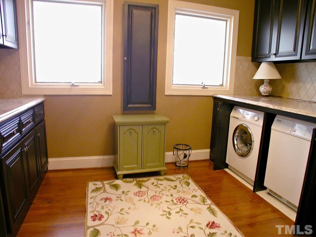 12200 Lockhart Lane Raleigh, NC 27614 - Photo 17 of 25 Beautiful and organized laundry room includes custom black-glazed maple cabinets, black granite composite laundry sink, porcelain blacksplash, tiled hanging area, built-in ironing board with Miele washer & dryer.