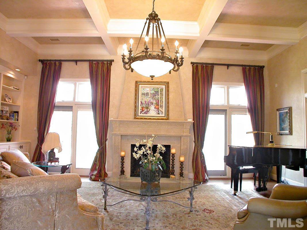 12200 Lockhart Lane Raleigh, NC 27614 - Photo 5 of 25 Lending further charm, the Great room infuses a decorative coffered ceiling with a lavish metropolitan chandelier, custom bookshelves and a majestic Scagliola stone hearth.