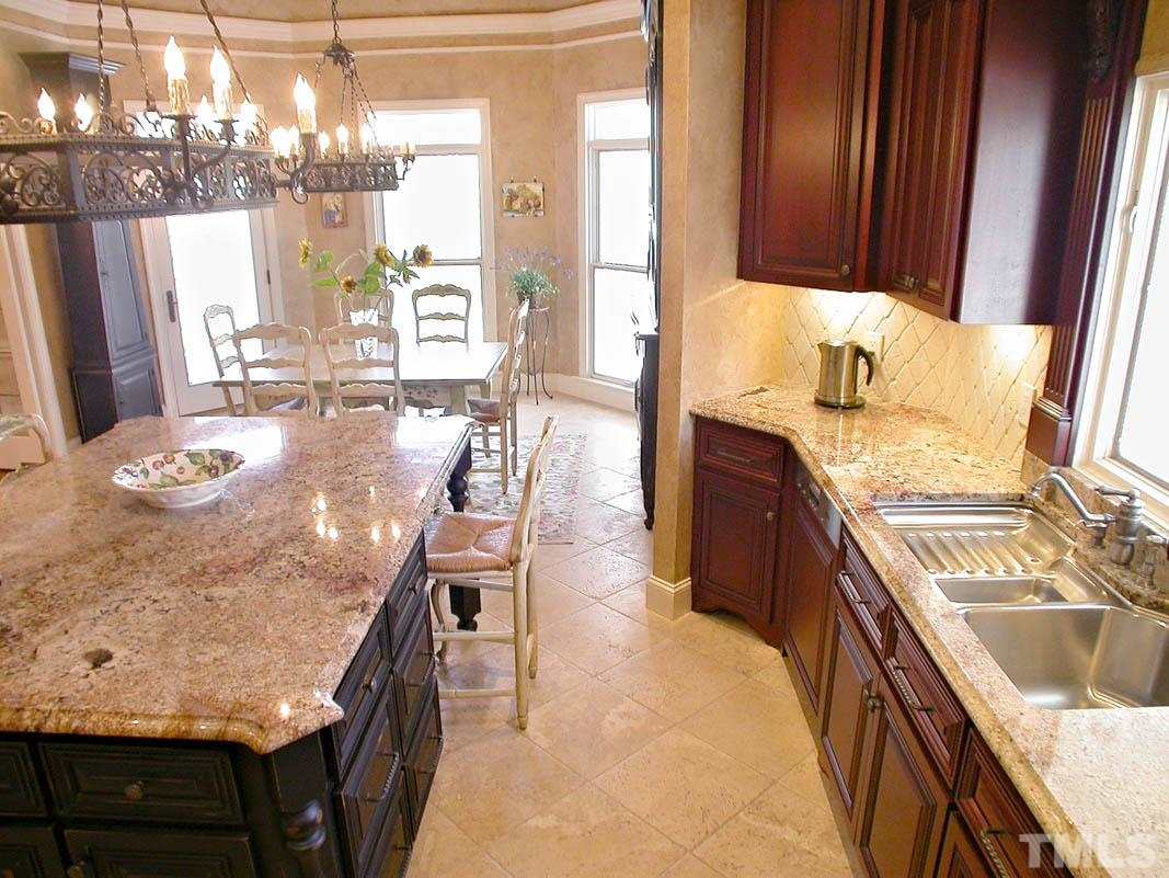 12200 Lockhart Lane Raleigh, NC 27614 - Photo 8 of 25 A gourmet chef's kitchen endowed with custom cherry cabinets, center island, granite countertops, custom mosaic art wall, 2 hand-forged wrought iron chandeliers (Art de Mexico), Chef's pantry, all designer appliances set on tumbled marble floors.