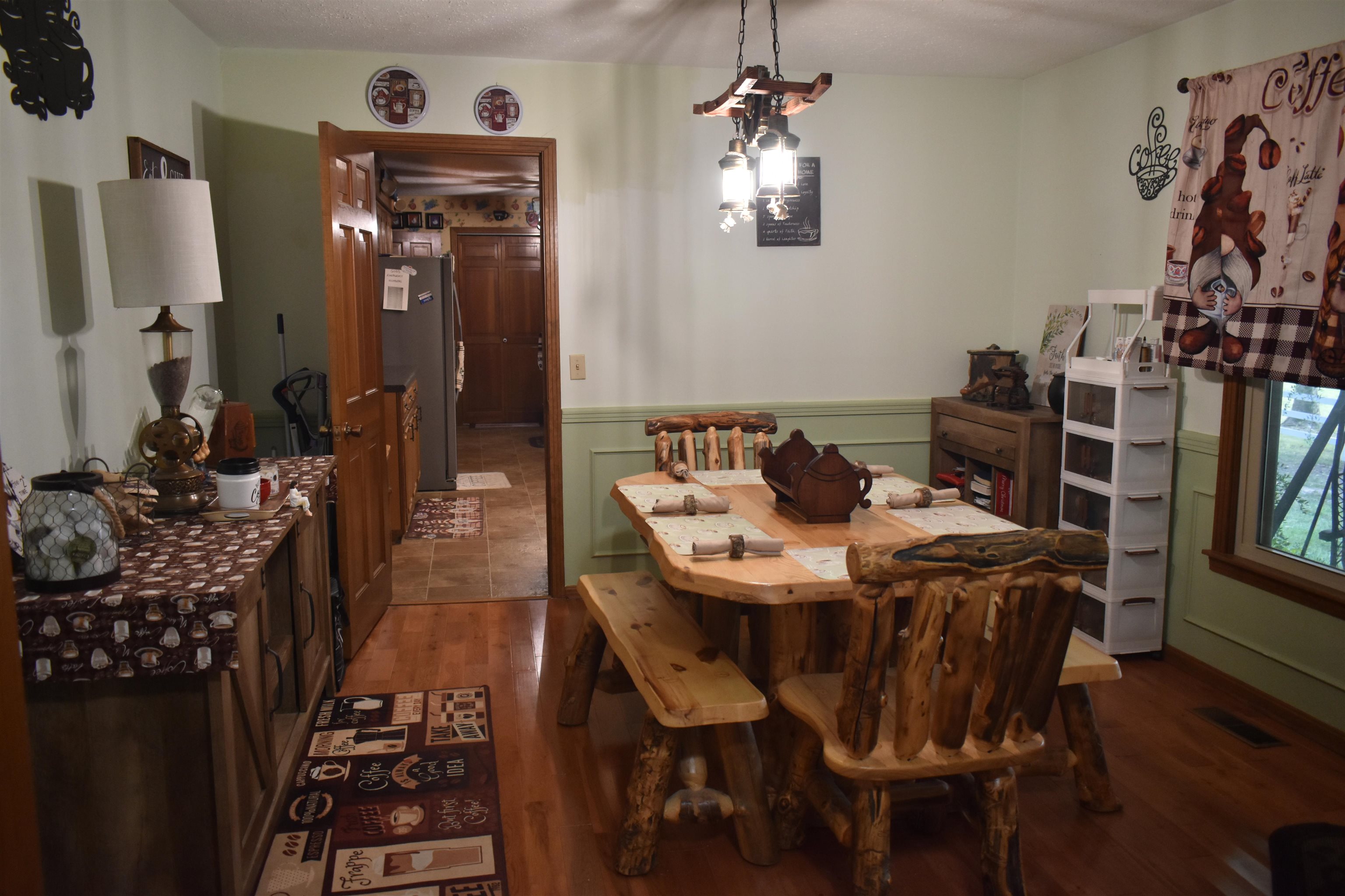 82 Ester Lane Ramer, TN 38367 - Photo 14 of 40 Hardwood flooring, light green walls, wood trim, dining area with a rustic wood table, and a window