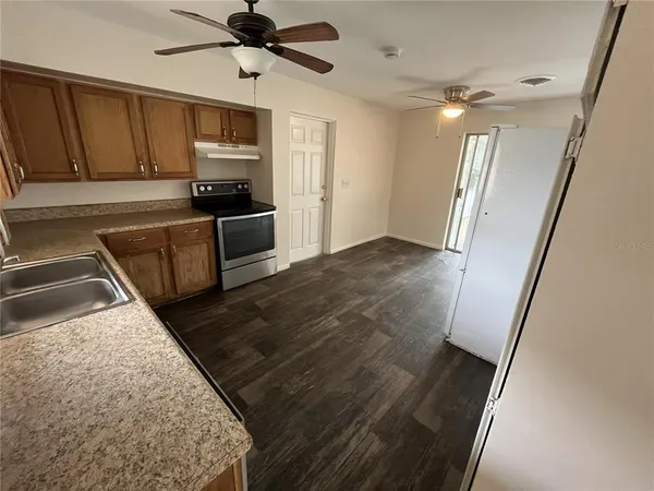 a kitchen with granite countertop a refrigerator oven a sink dishwasher and a stove with wooden floor