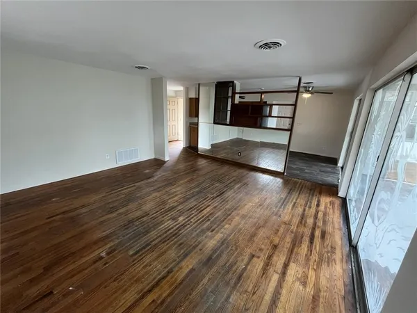 a view of wooden floor in an empty room with a window