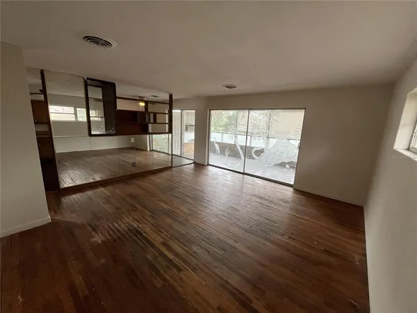 a view of an empty room with wooden floor and a window