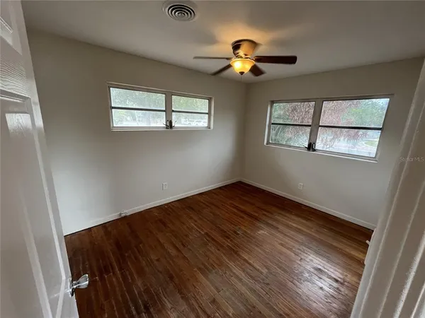 a view of empty room with wooden floor