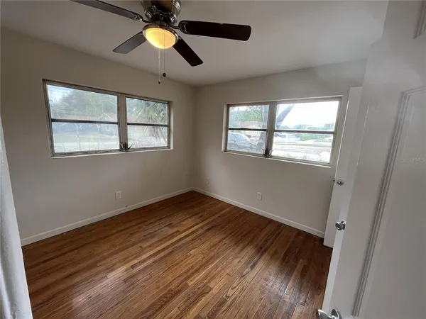 a view of an empty room with wooden floor and window