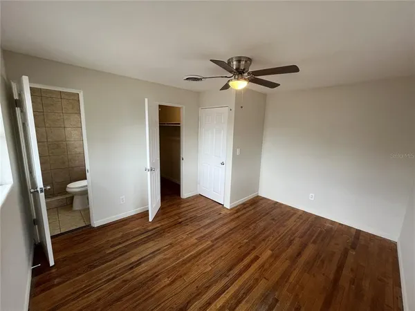 a view of empty room with wooden floor and fan