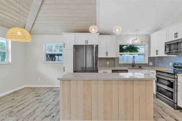 a kitchen with stainless steel appliances granite countertop a refrigerator a stove and a sink