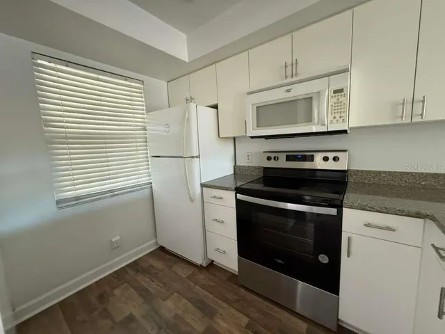 a kitchen with stainless steel appliances white cabinets and a stove top oven