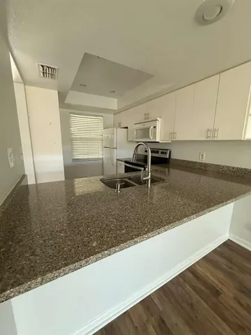 a kitchen with granite countertop a sink and a stove top oven