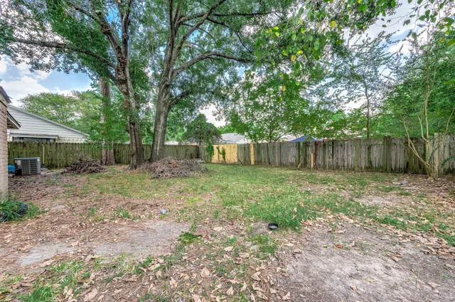 a view of a backyard with large trees and wooden fence
