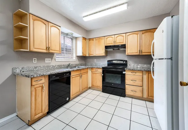 a kitchen with granite countertop a stove sink and cabinets