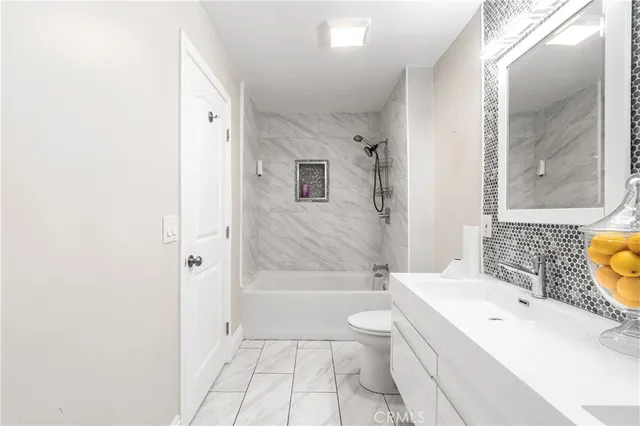 a bathroom with a bathtub shower sink mirror vanity and a toilet