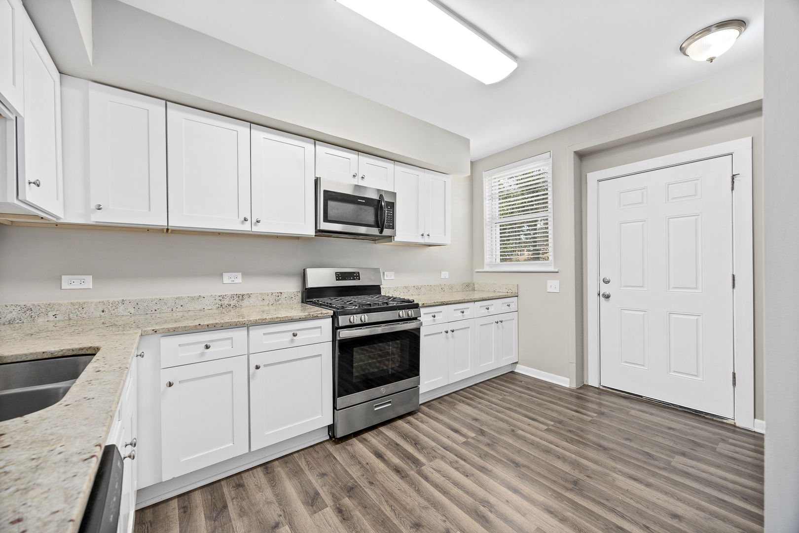 6535 26th Place Berwyn, IL 60402 - Photo 12 of 26 a kitchen with granite countertop white cabinets a sink dishwasher a stove and a refrigerator with wooden floor