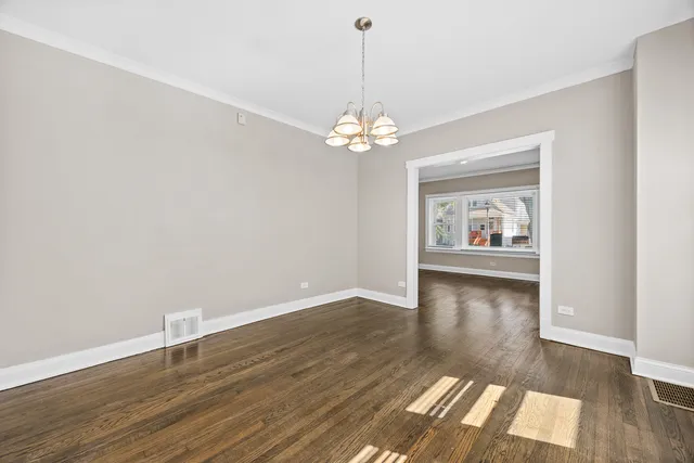 a view of a room with wooden floor chandelier and a window