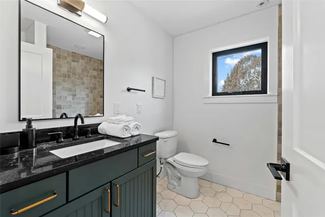 a bathroom with a granite countertop toilet a sink and a mirror