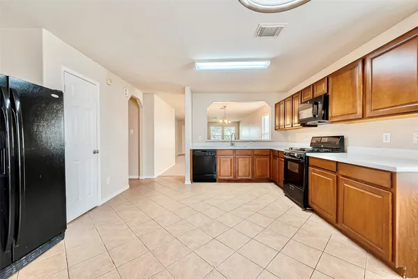 a large kitchen with stainless steel appliances kitchen island granite countertop a refrigerator and a sink
