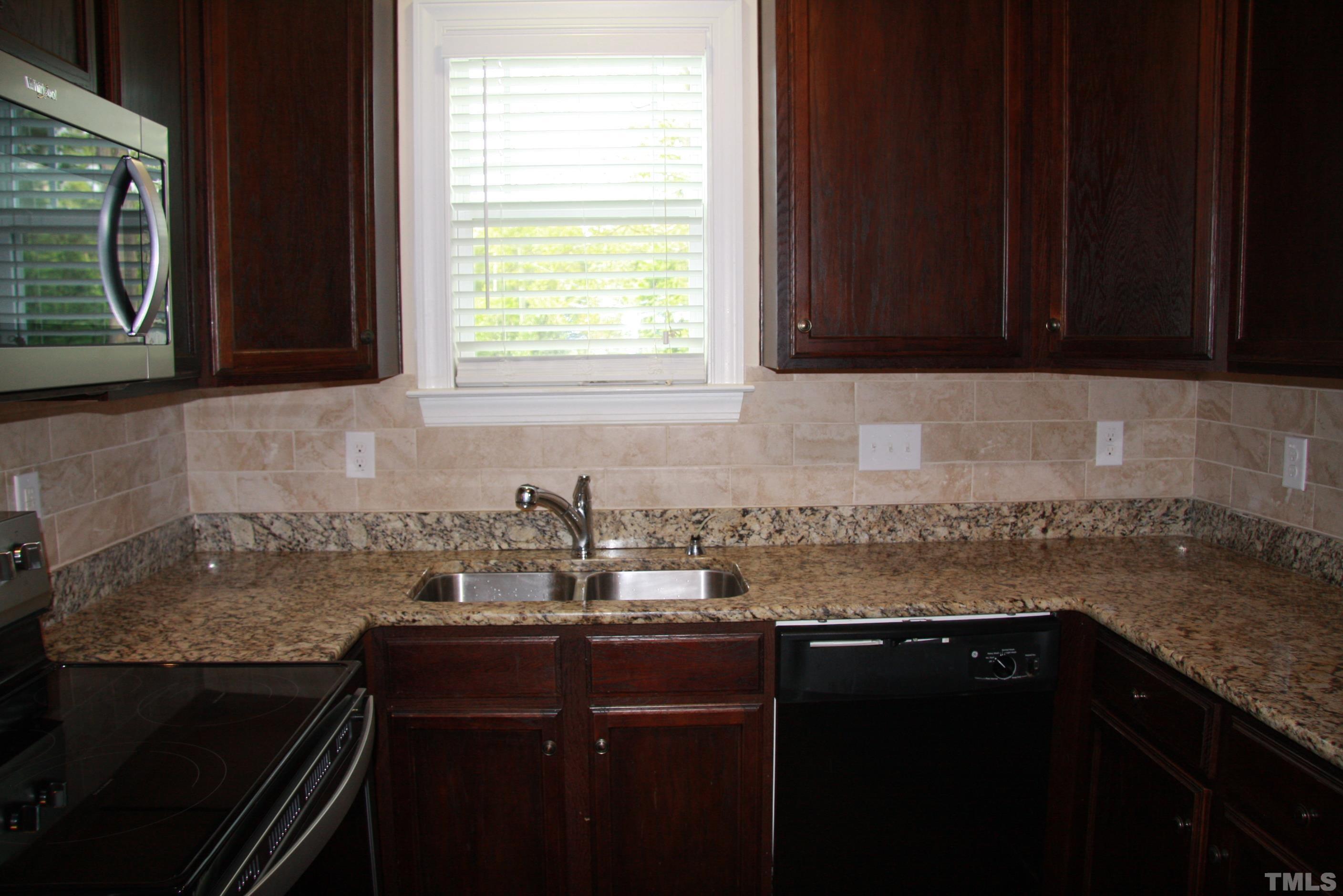 2021 Chancellor Place Raleigh, NC 27603 - Photo 11 of 30 a kitchen with a sink a stove cabinets and a window