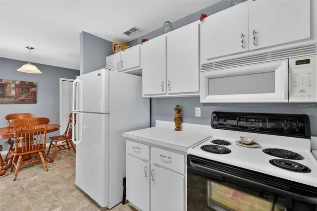 a kitchen with a refrigerator a stove a sink and a dining table with chairs