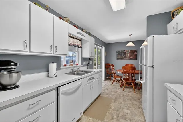 a kitchen with a sink dishwasher a refrigerator and cabinets with wooden floor