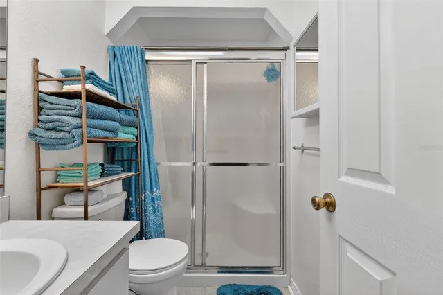 a bathroom with a granite countertop bathtub shower sink vanity and toilet